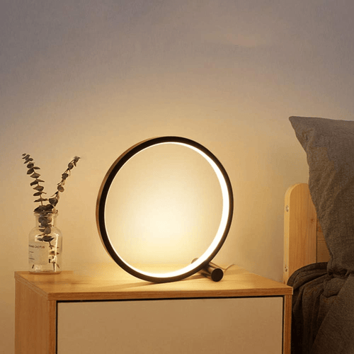 Lámpara anillo led junto a una cama