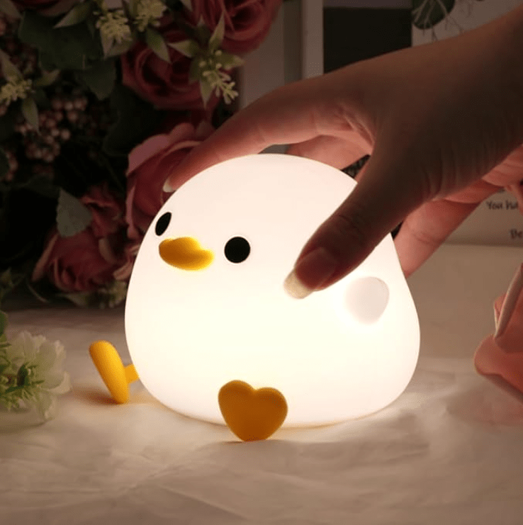 Mano tocando lámpara pato infantil encendida